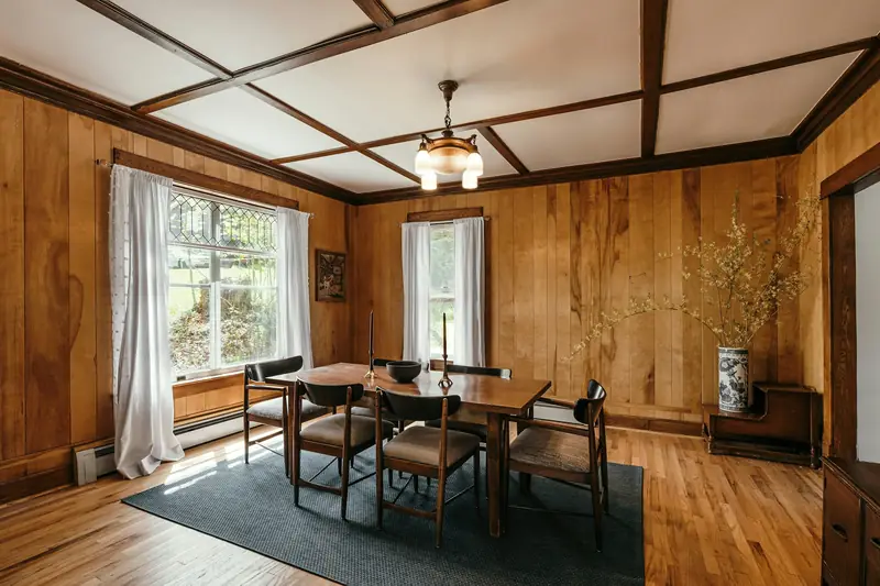 Sala de jantar com mesa e paredes revestidas em madeira